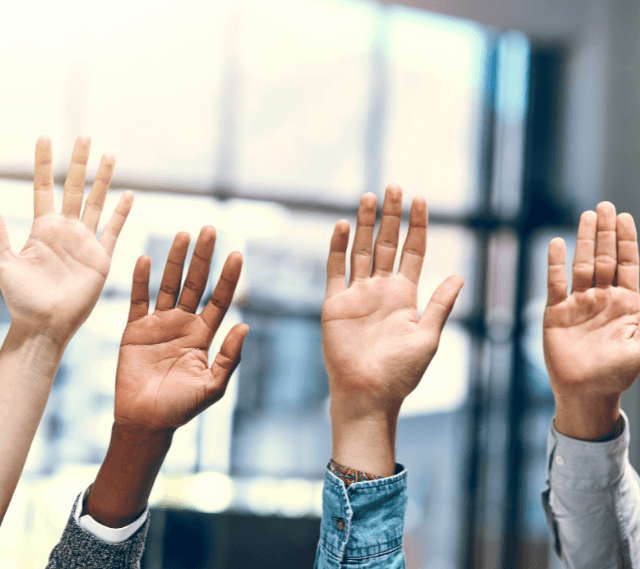 group of people raising their hands in question